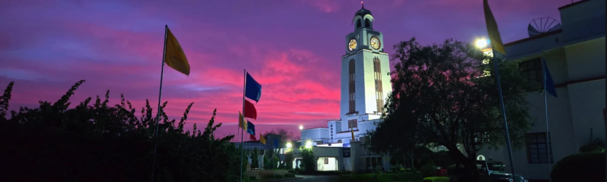 BITS Pilani campus at dusk, the clock tower lit against a violet sky